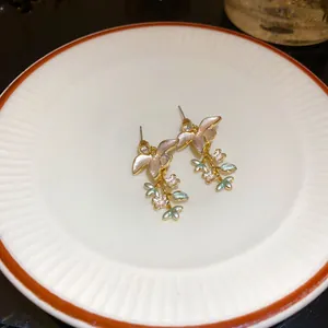 Dettaglio di eleganti orecchini a lobo con fiori in smalto e cristalli scintillanti