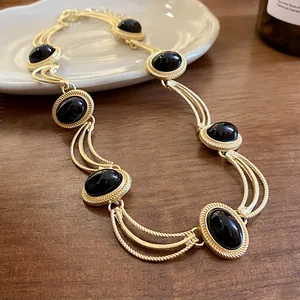 Détail rapproché d'un collier de style vintage avec des pierres noires et une chaîne dorée