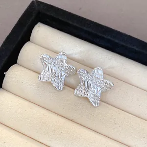 Close-up of silver textured star stud earrings with an intricate mesh pattern