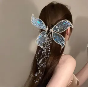 Détail d'une pince à cheveux papillon bleu irisé avec de longs glands en perles