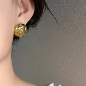 Detailed close-up of a golden pleated ripple texture stud earring on an Asian model