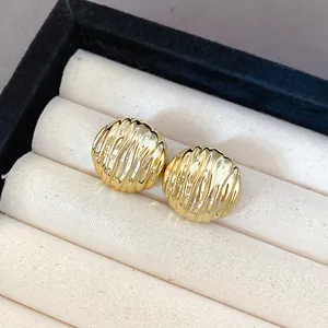 Detail shot of gold ripple textured stud earrings displayed in a luxury cream jewelry box