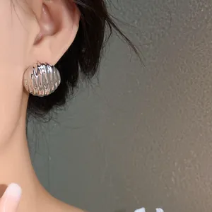 Macro view of high-shine silver pleated water drop earring worn on a model's ear