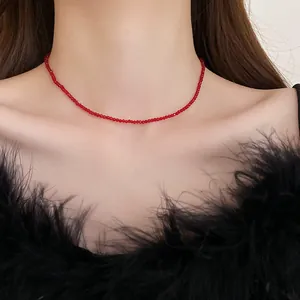Close-up view of a minimalist red beaded choker necklace worn on the neck of a model