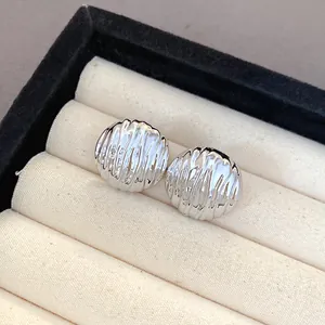 Detailed view of silver-colored pleated texture earrings in a jewelry box slot.