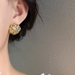Close-up detail of a gold quilted pattern stud earring worn by a model in soft light