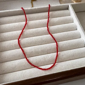 Detail view of red beaded choker necklace in a beige jewelry display tray