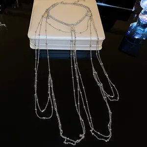 Hochwertiges Detail einer mehrlagigen silbernen Körperkette mit Zirkonia und Perlen.