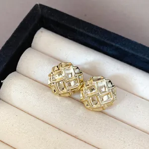 Macro detail of elegant gold-tone stud earrings with a stylish quilted textured design.