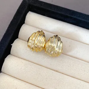 Detailed close-up of golden water-drop stud earrings with elegant pleated texture