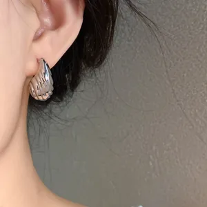 Detailed view of shiny silver ribbed droplet earring worn on ear with elegant finish