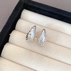 Macro detail of silver-toned pleated teardrop stud earrings in a jewelry box.