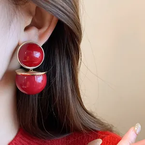 Detailed close-up of retro double-tier round red stud earrings with gold trim on model