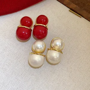 Close-up of retro double sphere stud earrings in vibrant red and pearl white finish.
