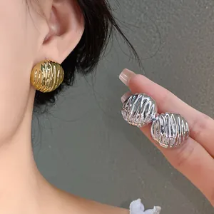 Detailed macro view of gold and silver ridged stud earrings with elegant texture