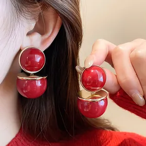 Elegant detail of vintage red round stud earrings with silver needles on an Asian model