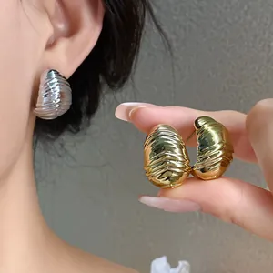 Detailed view of pleated textured water drop earrings in gold and silver metallic finishes.