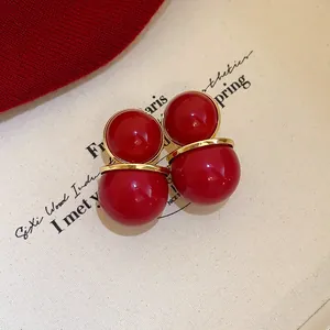 Close-up of retro Ankara red circular earrings with high-gloss finish and gold trim.