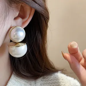 Detailed view of elegant double stacked white faux pearl stud earrings on model