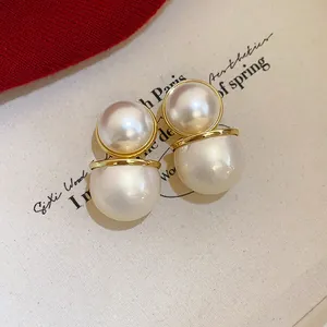 Close-up of vintage double pearl earrings with gold accents and silver needles
