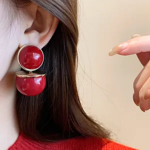 Detail view of retro red double round drop earrings with glossy finish as worn on the ear