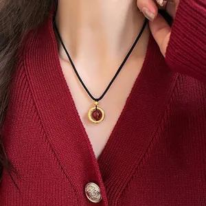 Close-up detail of a red agate Ping'an Kou necklace featuring a gold pendant on a black cord