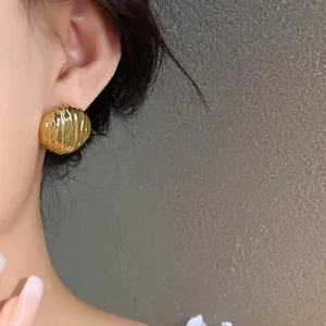Close-up of elegant golden ribbed acrylic stud earrings featuring a chic vintage design