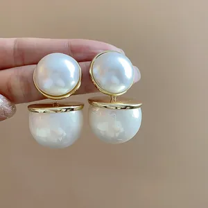 Detailed macro view of elegant double pearl drop earrings featuring gold metal disks