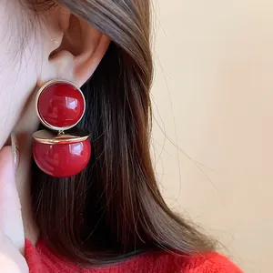 Close-up of vintage style red round earrings with gold-tone accents worn on the ear.