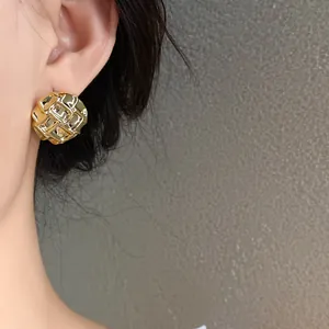 Macro view of elegant golden pleated grid stud earring showing textured metal finish