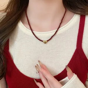 Close-up of a red agate beaded necklace featuring a gold heart pendant worn on an Asian model