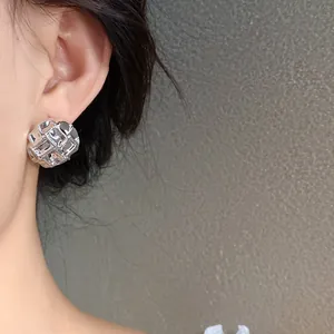Close-up view of elegant silver pleated geometric stud earrings on a model's ear.