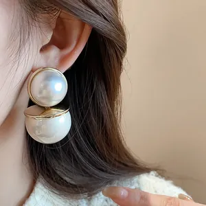 Detail view of elegant vintage double white pearl drop earrings with gold metal accents