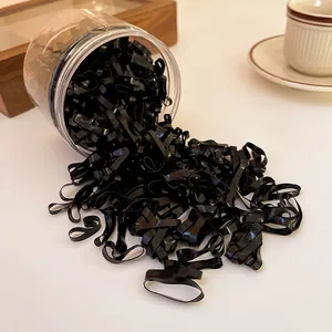 Detail view of black disposable hair bands spilling out of a transparent storage jar.
