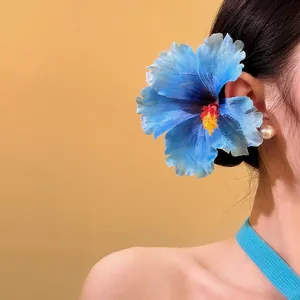 Side view of model wearing a large blue fabric hibiscus flower hair clip accessory