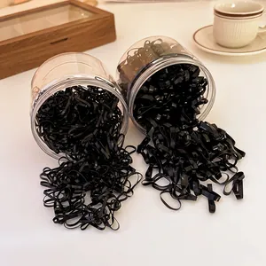Set of black disposable elastic hair ties spilling from transparent storage jars
