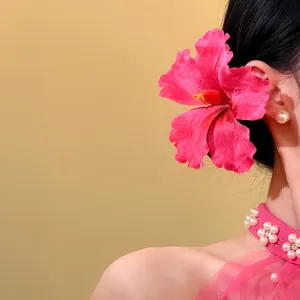 Side view detail of a vibrant pink fabric hibiscus flower hair accessory styled in black hair