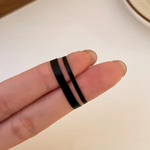 Detailed view of two black disposable elastic rubber bands with different widths on fingers.