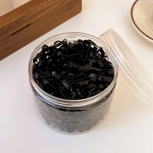 Detailed view of disposable black hair elastics inside a transparent storage jar