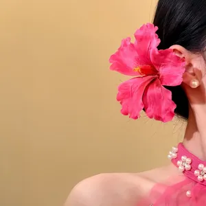 Detail view of a large pink fabric hibiscus flower hairpin worn elegantly behind the ear