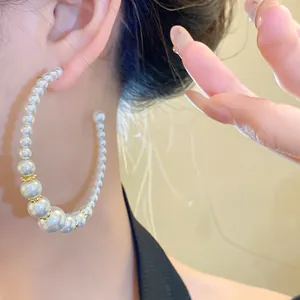 Primo piano di eleganti orecchini a cerchio a C con perle bianche graduate.