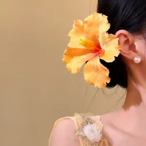 Close-up detail view of a yellow fabric flower hair pin worn on a model's side hair