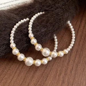 Dettaglio delle eleganti orecchini a cerchio a C con perle bianche sfumate e accenti dorati