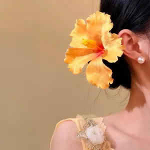 Close-up view of an elegant yellow fabric hibiscus flower hairpin worn on model's head