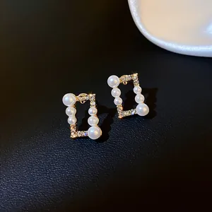 Dettaglio di eleganti orecchini rettangolari in oro con perle e cristalli in stile vintage
