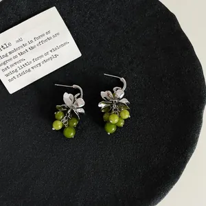 Detail van zilveren bloemoorbellen met groene glazen druifvormige kralen, elegant