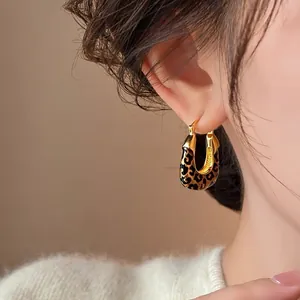 Close-up detail of elegant gold hoop earrings featuring vintage leopard print enamel
