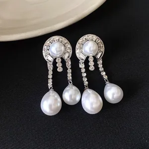 Détail de boucles d'oreilles pendantes élégantes avec strass et perles blanches brillantes