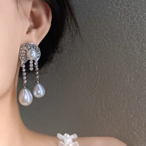 Détail rapproché de boucles d'oreilles pendantes argentées avec perles et cristaux.