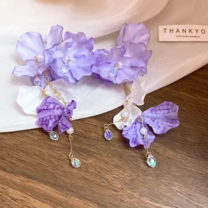 Gros plan sur des boucles d'oreilles fleur en tulle violet avec glands en cristal